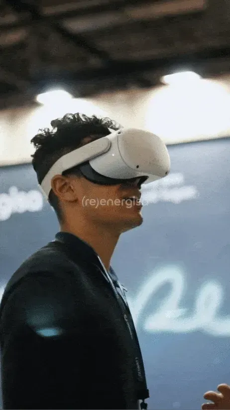 mK VR (ativação em realidade virtual/metaverso): participante usando óculos de realidade virtual em ativação de marca com o slogan '(re)energiza' ao fundo